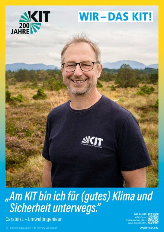 Umweltingenieur im KIT-T-Shirt steht in einer offenen Landschaft mit Bergen im Hintergrund.